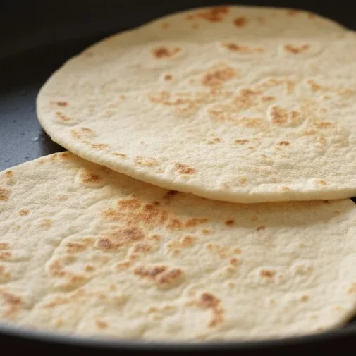 Flour tortillas warming in a skillet until soft and pliable.